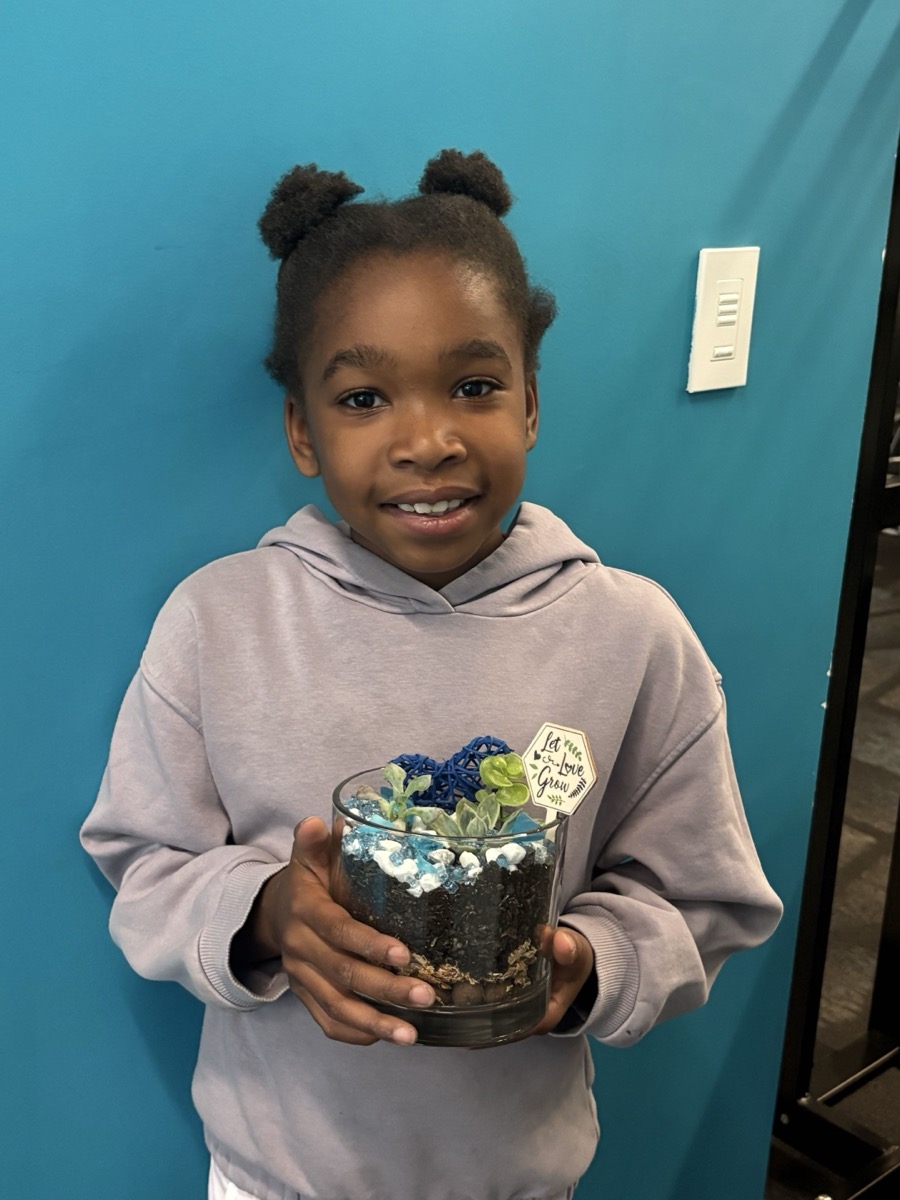 A proud child holding up their finished terrarium