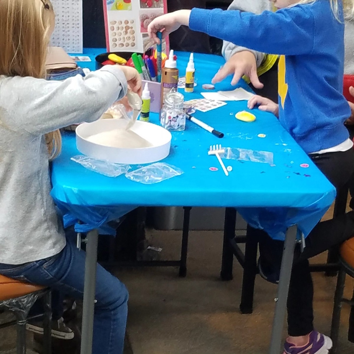 Two children building sand-art terrariums at a Now and Zen kids party table