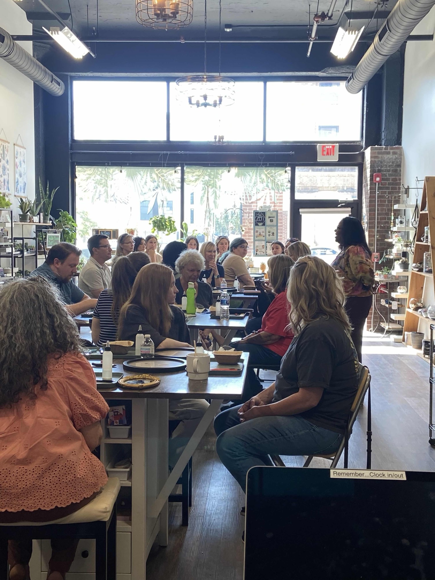A full workshop crowd seated at long tables building terrariums together near the storefront windows