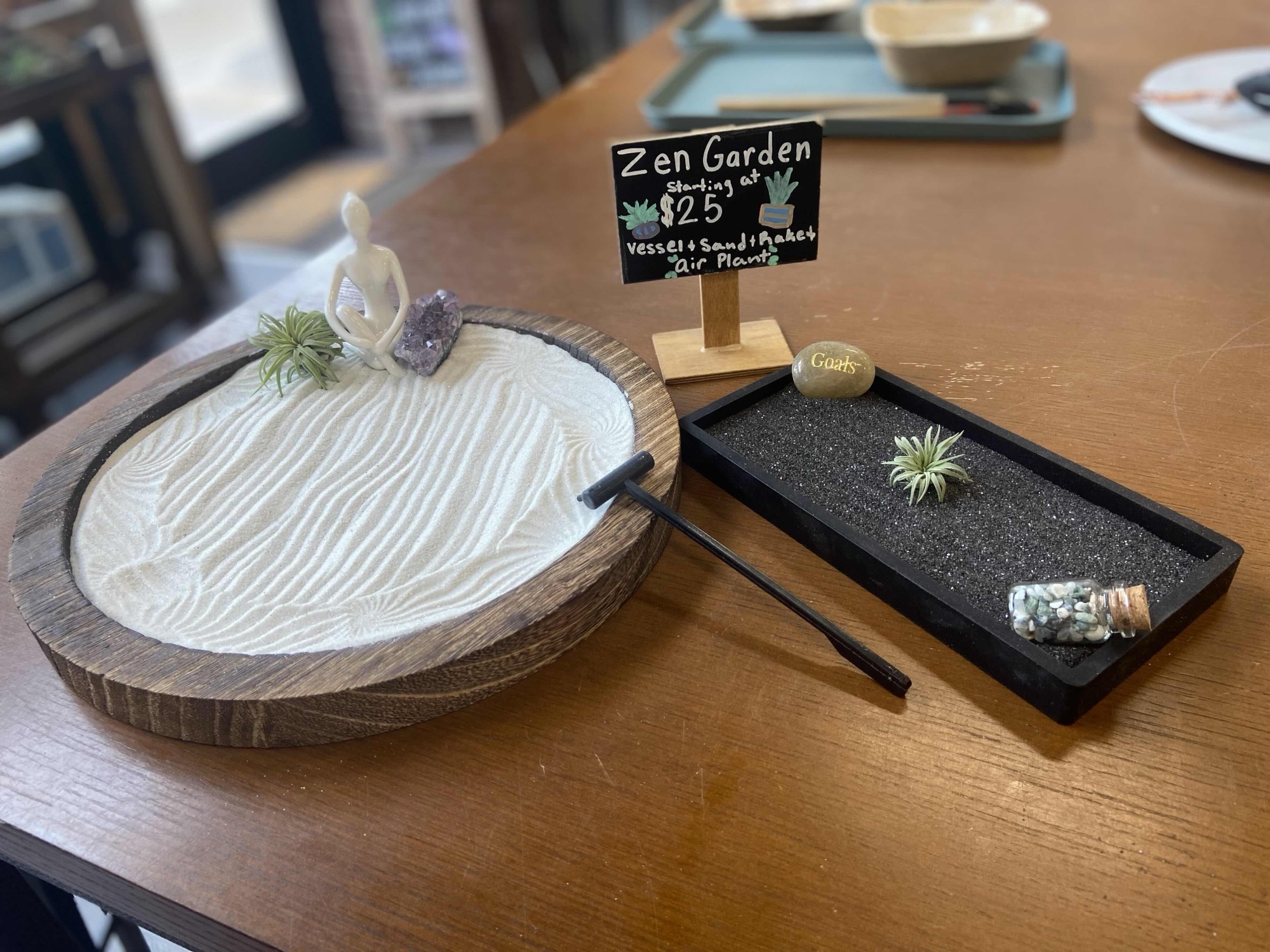 A finished zen garden with layered sand, stones, and small plants